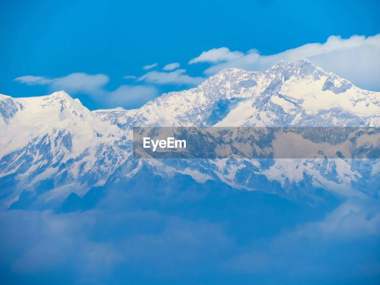 Scenic view of snowcapped mountains against blue sky