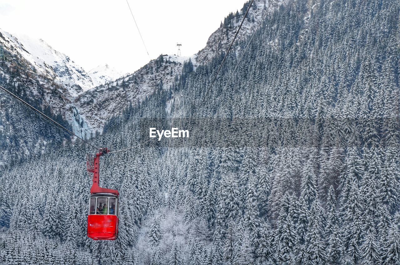 Red overhead car against trees on mountain