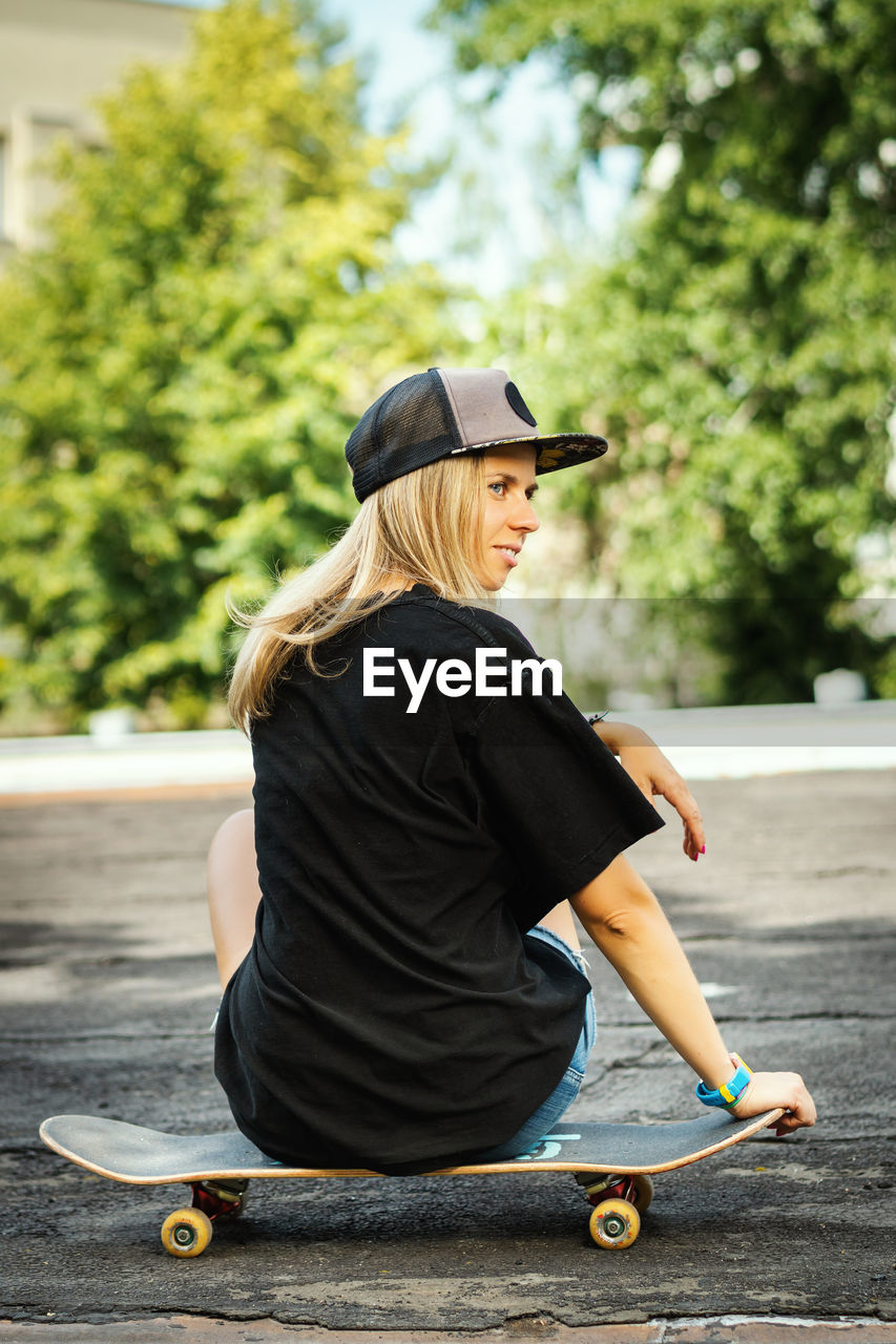 Rear view of woman sitting on skateboard