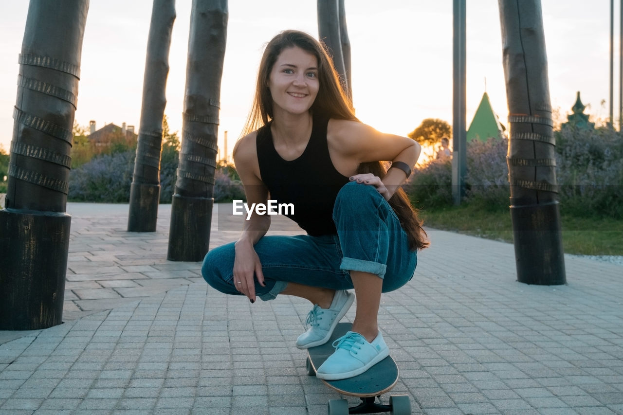 PORTRAIT OF SMILING YOUNG WOMAN OUTDOORS