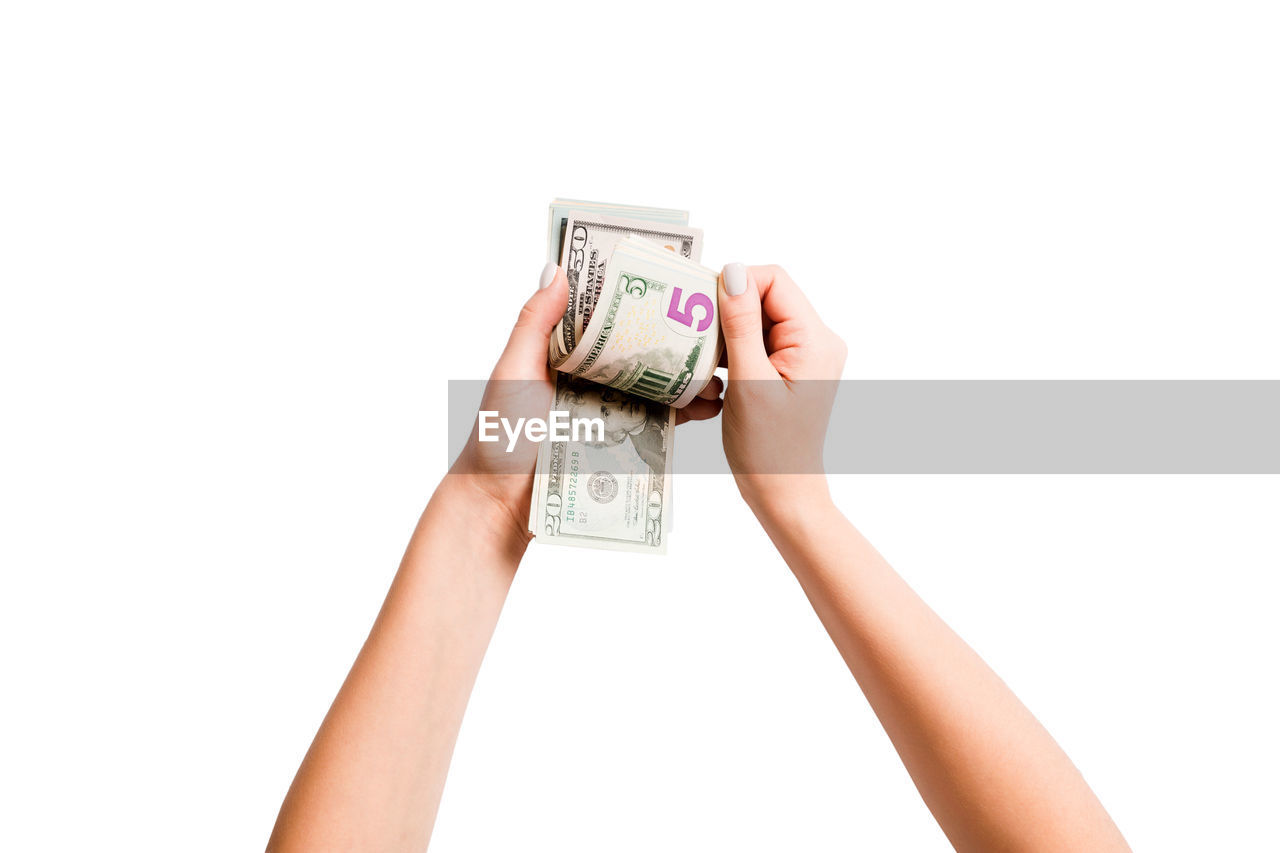 Cropped hands of woman counting paper currency against white background