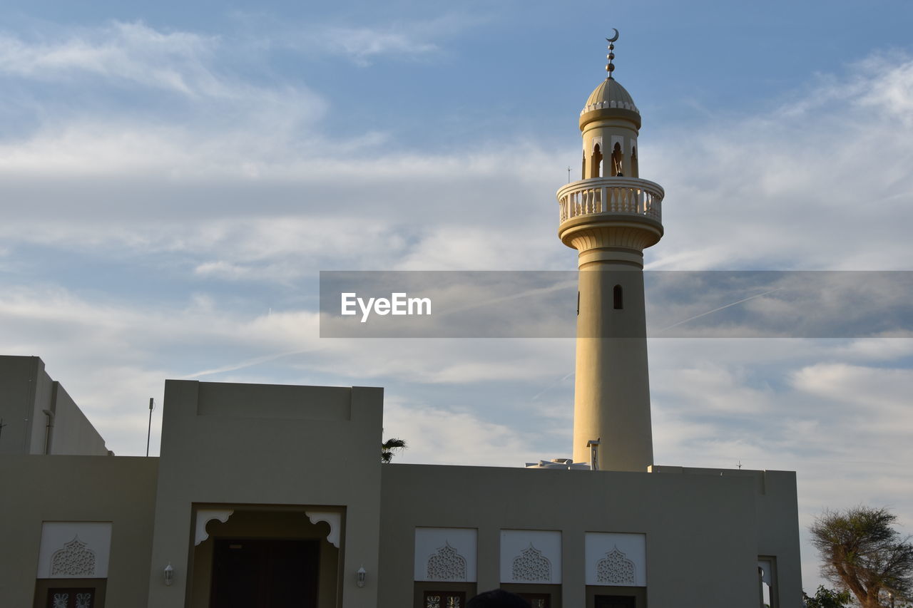 Low angle view of mosque against cloudy sky