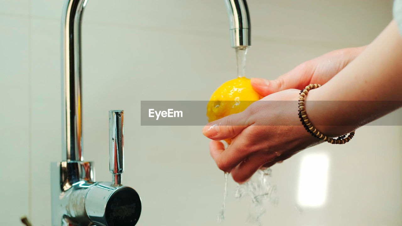 CLOSE-UP OF WOMAN HAND HOLDING WATER IN BATHROOM