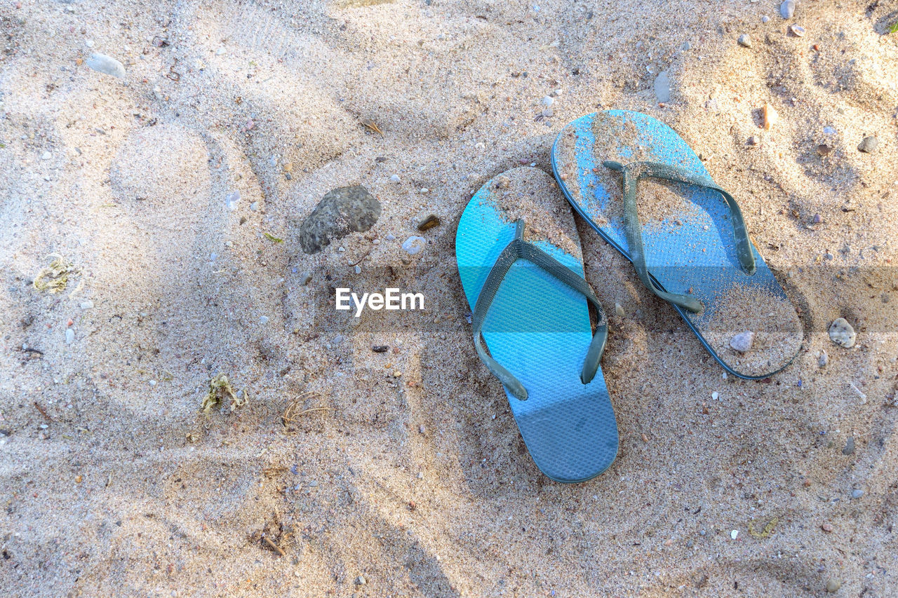 sand, beach, land, blue, flip-flops, high angle view, nature, footwear, day, no people, shoe, sandal, pair, absence, outdoors, sunlight, green, still life, rock, abandoned, water