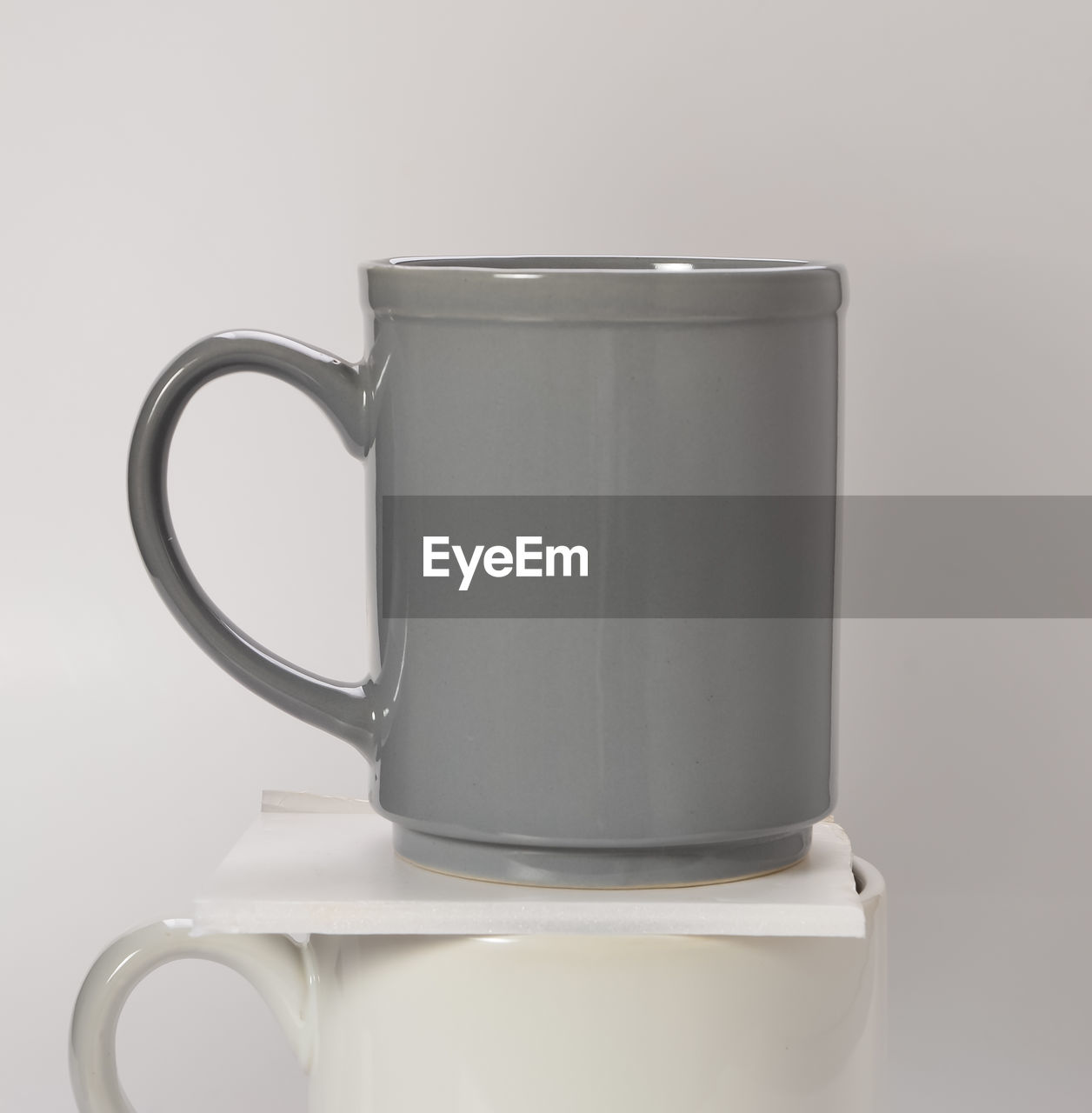 Close-up of gray and white coffee cups against white background