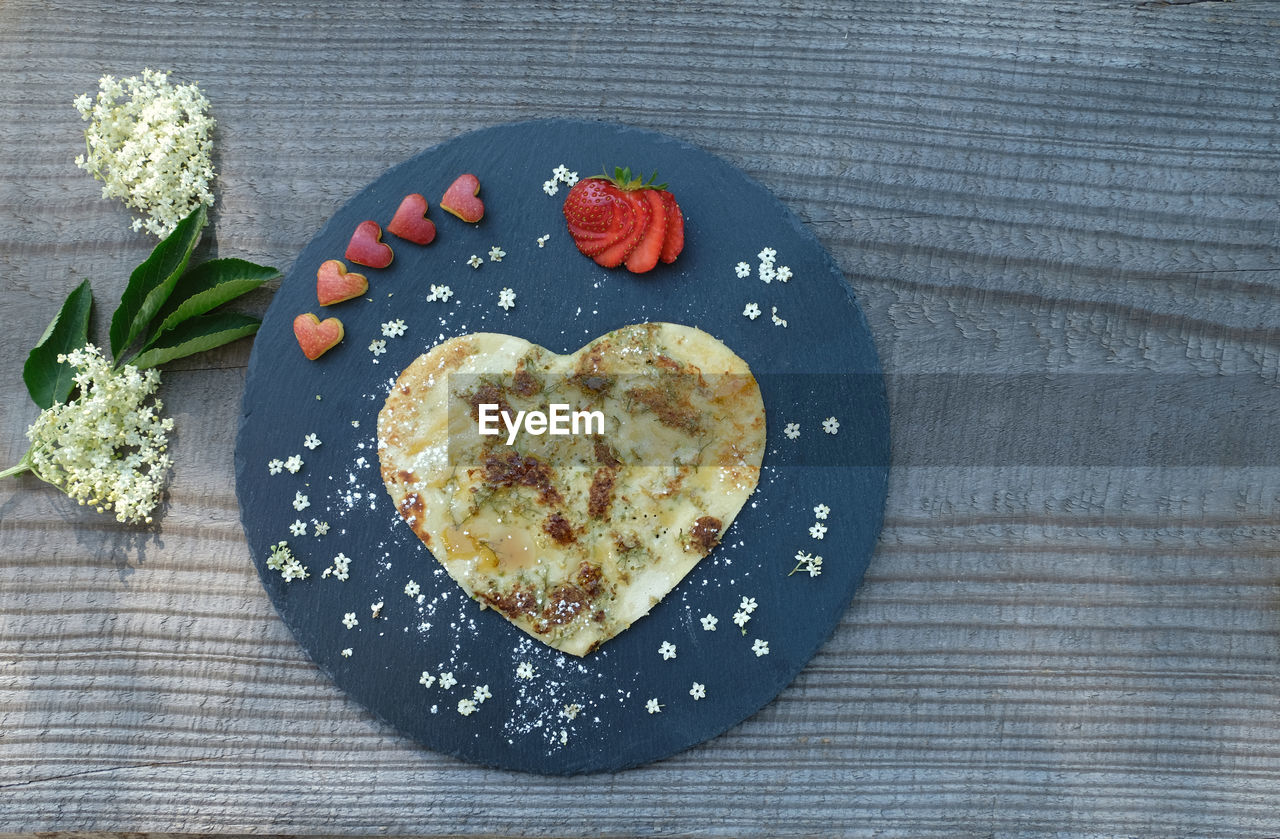 Heart shaped pancake with sambucus flower. garnished with five heart shaped red apple.