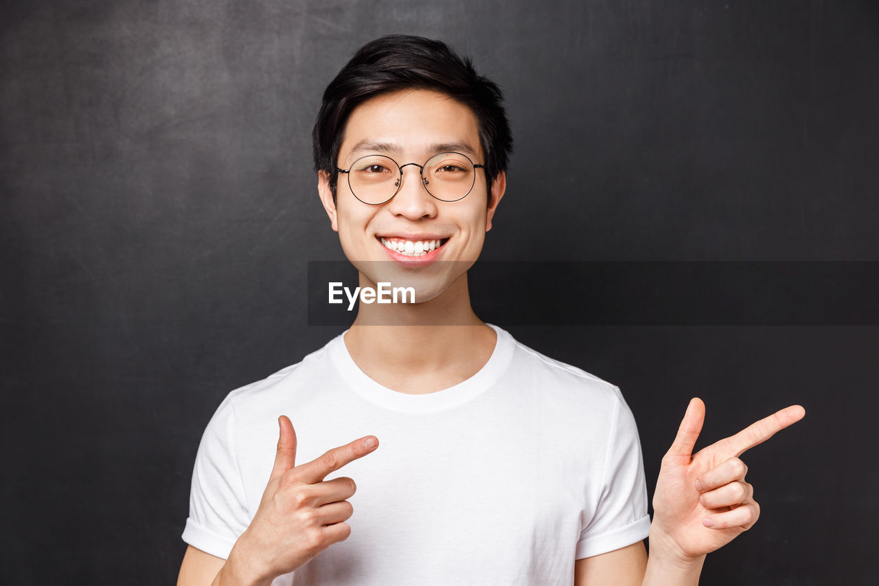 Portrait of smiling man standing against black background