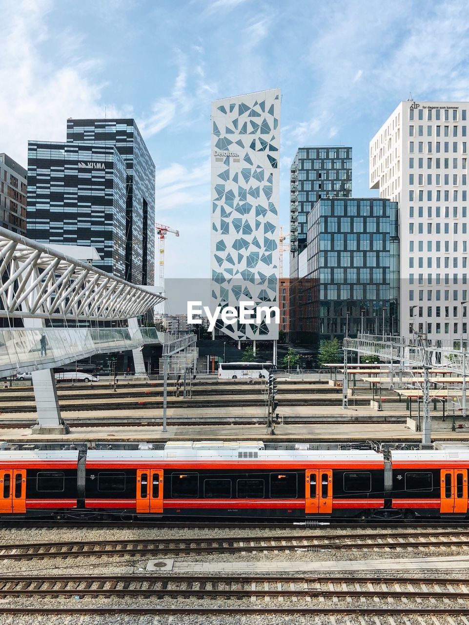 Train passing by buildings in city against sky