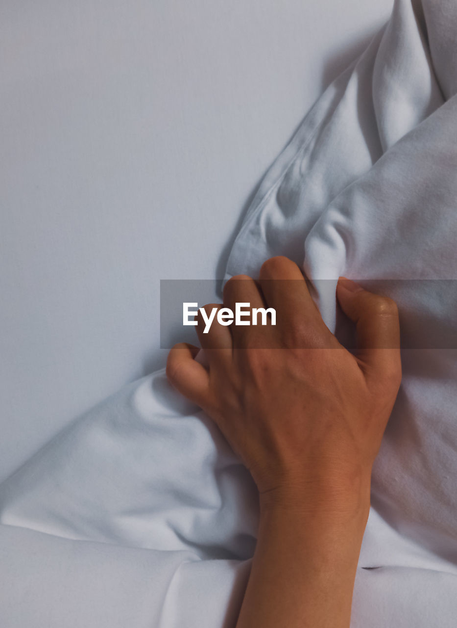 Low section of woman with hands on bed at home
