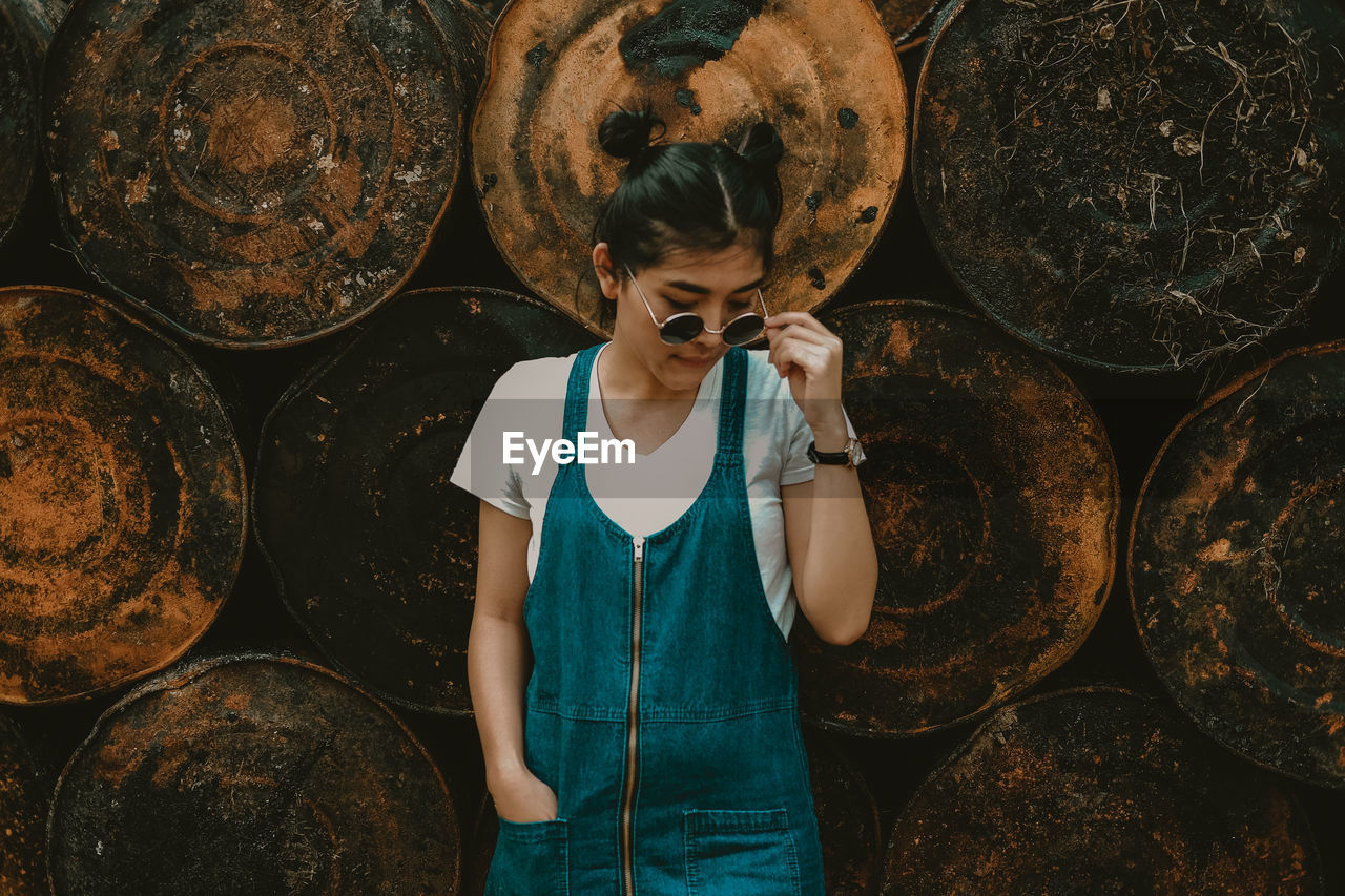 YOUNG WOMAN STANDING ON A STACK OF A LOGS