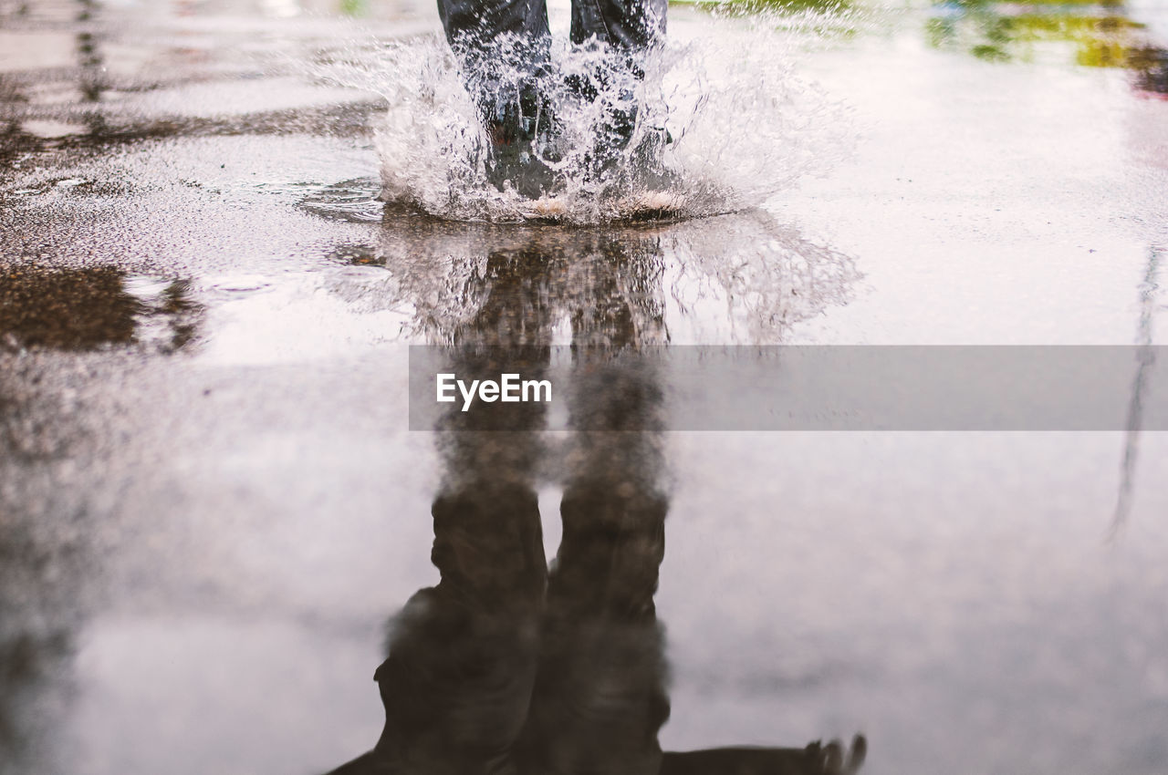 Reflection of person splashing in puddle