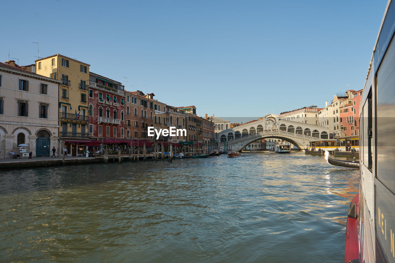 Arch bridge over river amidst buildings in city against sky rialto venice canal grande