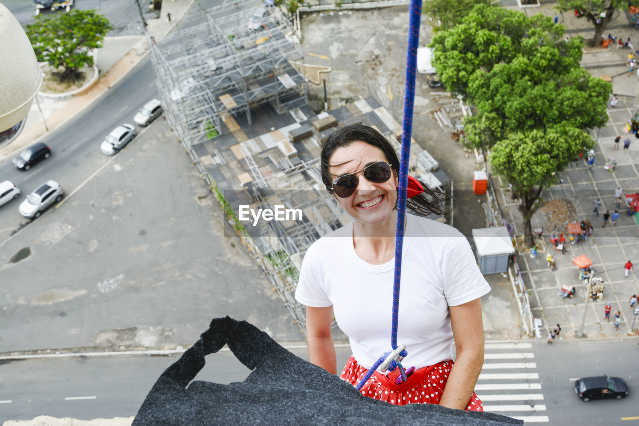 Caucasian woman wearing hero costume descending a tall building in rappel. salvador bahia brazil.