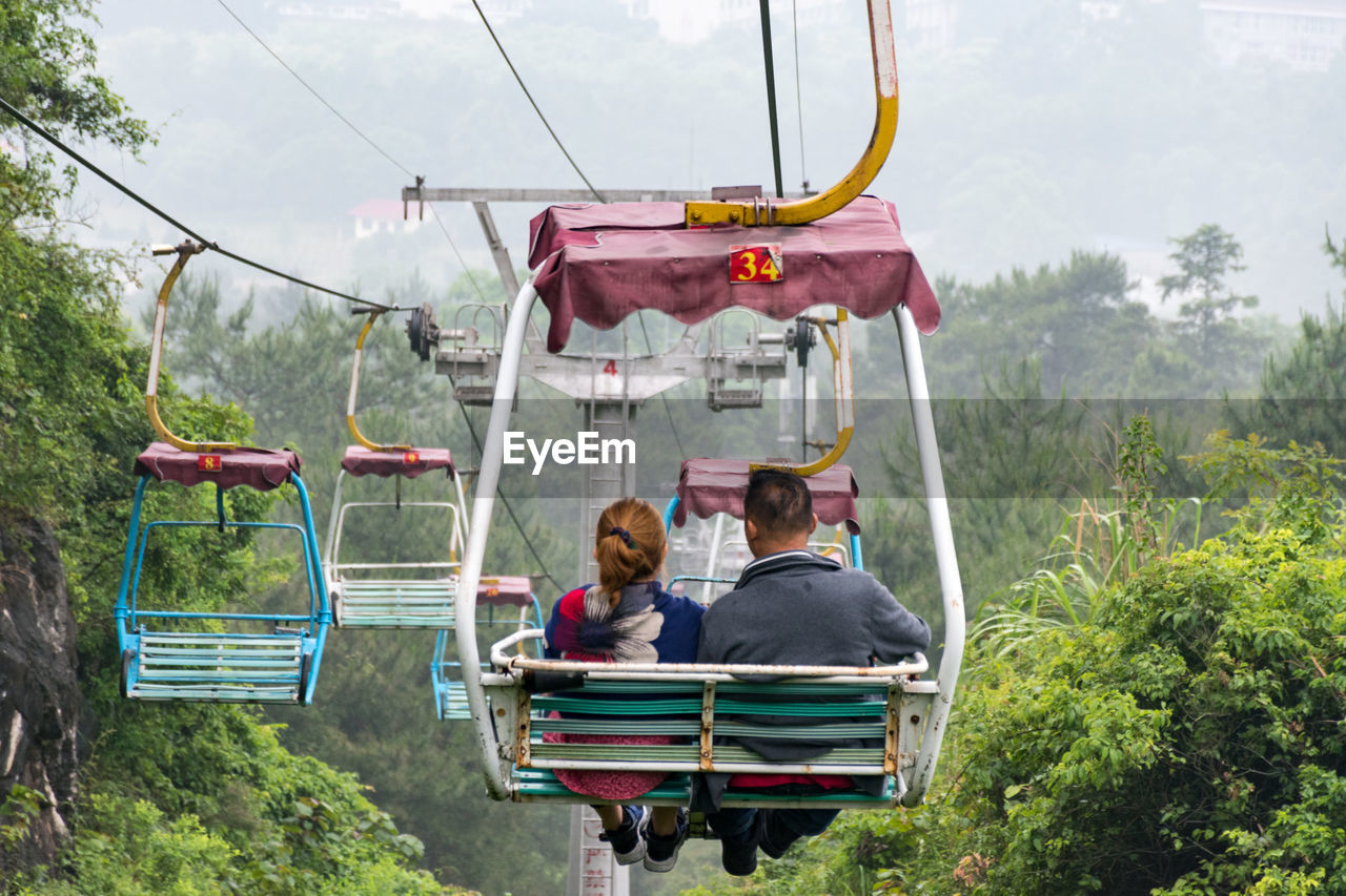 Rear view of man and woman sitting on overhead cable car