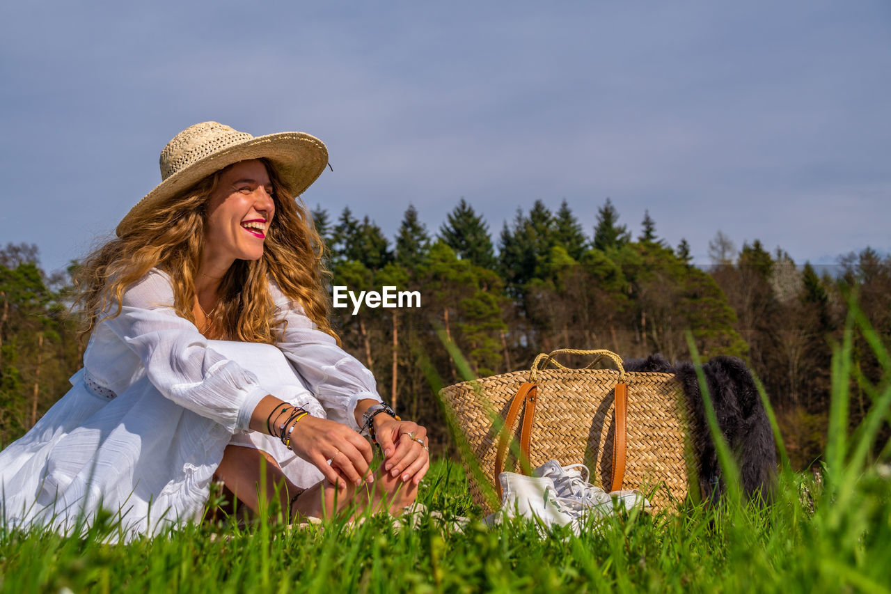 Smiling woman wearing hat sitting on grass