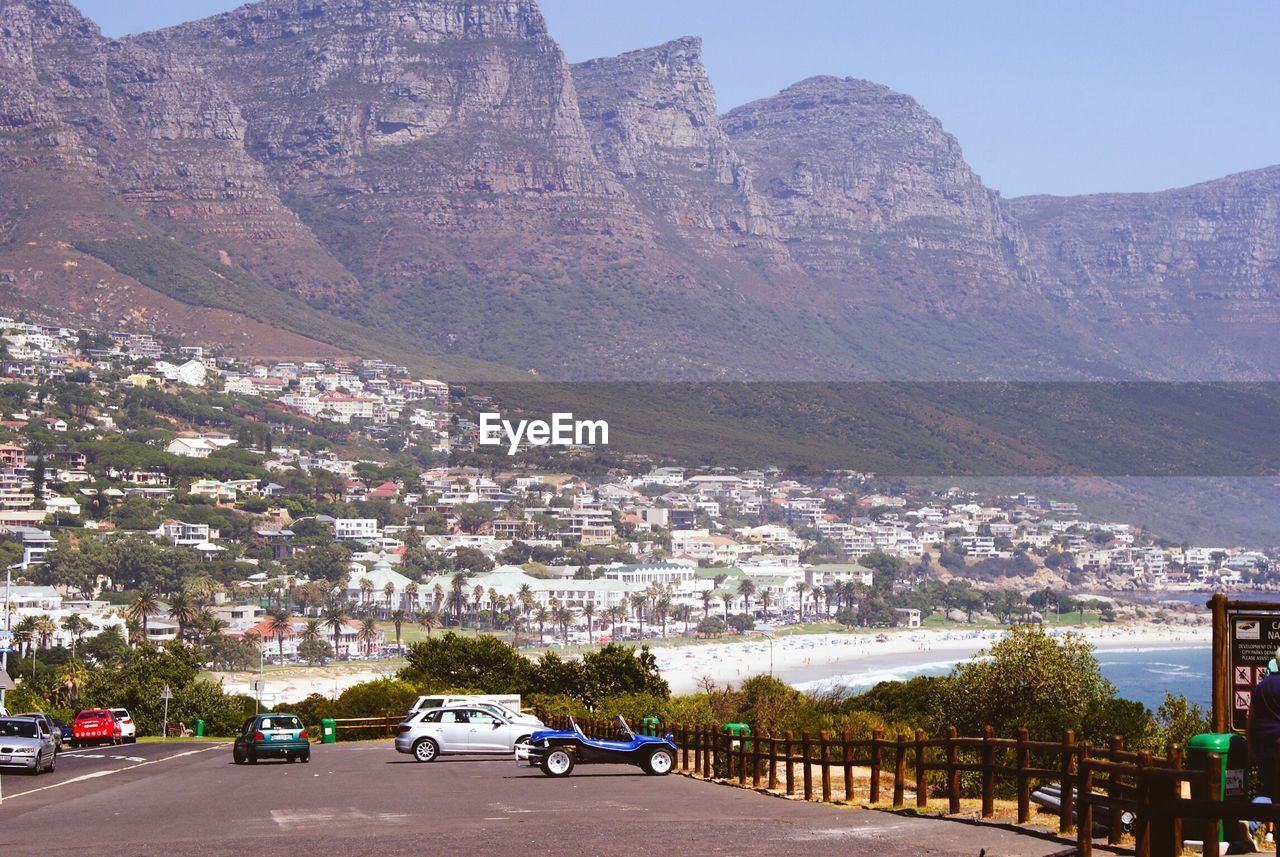 Cars on road by cityscape against clear sky