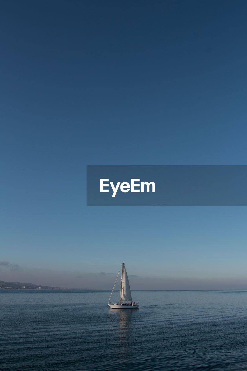 Sailboat sailing on sea against clear sky