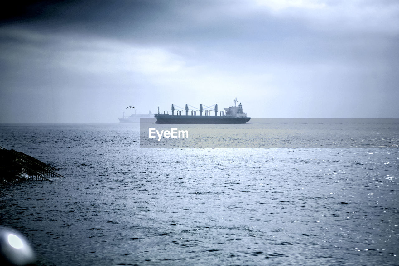 Boats on sea against cloudy sky