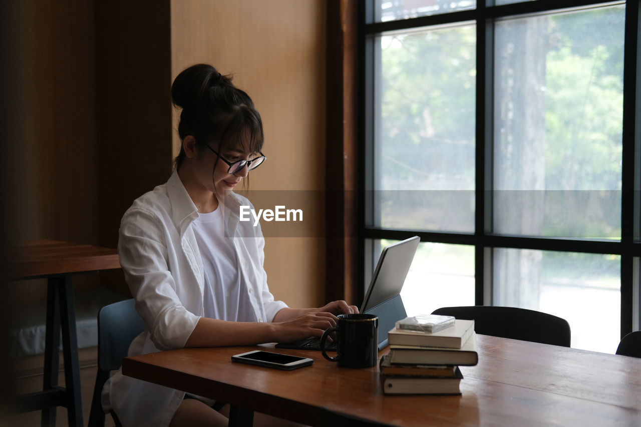 Woman using phone while sitting on table