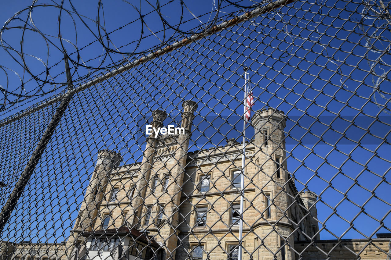 Abandoned historic prison through chain fence