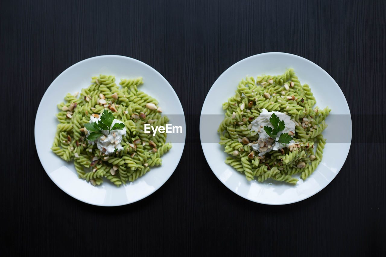 Close-up of served green pasta on two plates