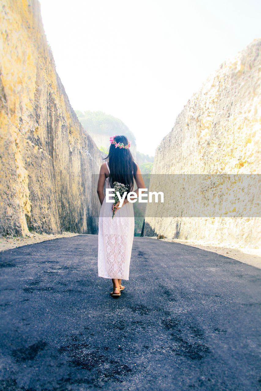 Rear view of woman standing on road against clear sky