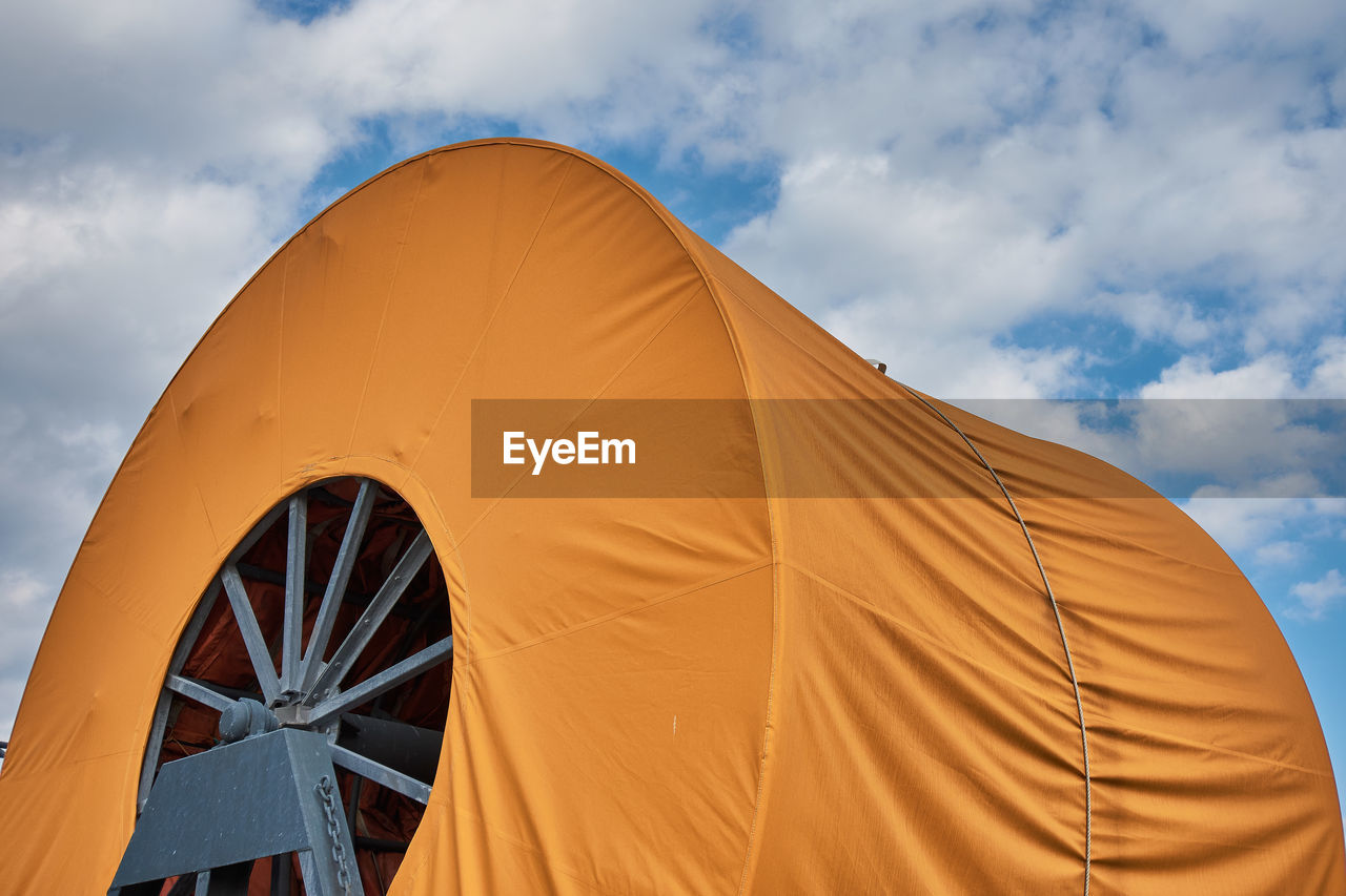 Low angle view of canvas cover over machinery against sky