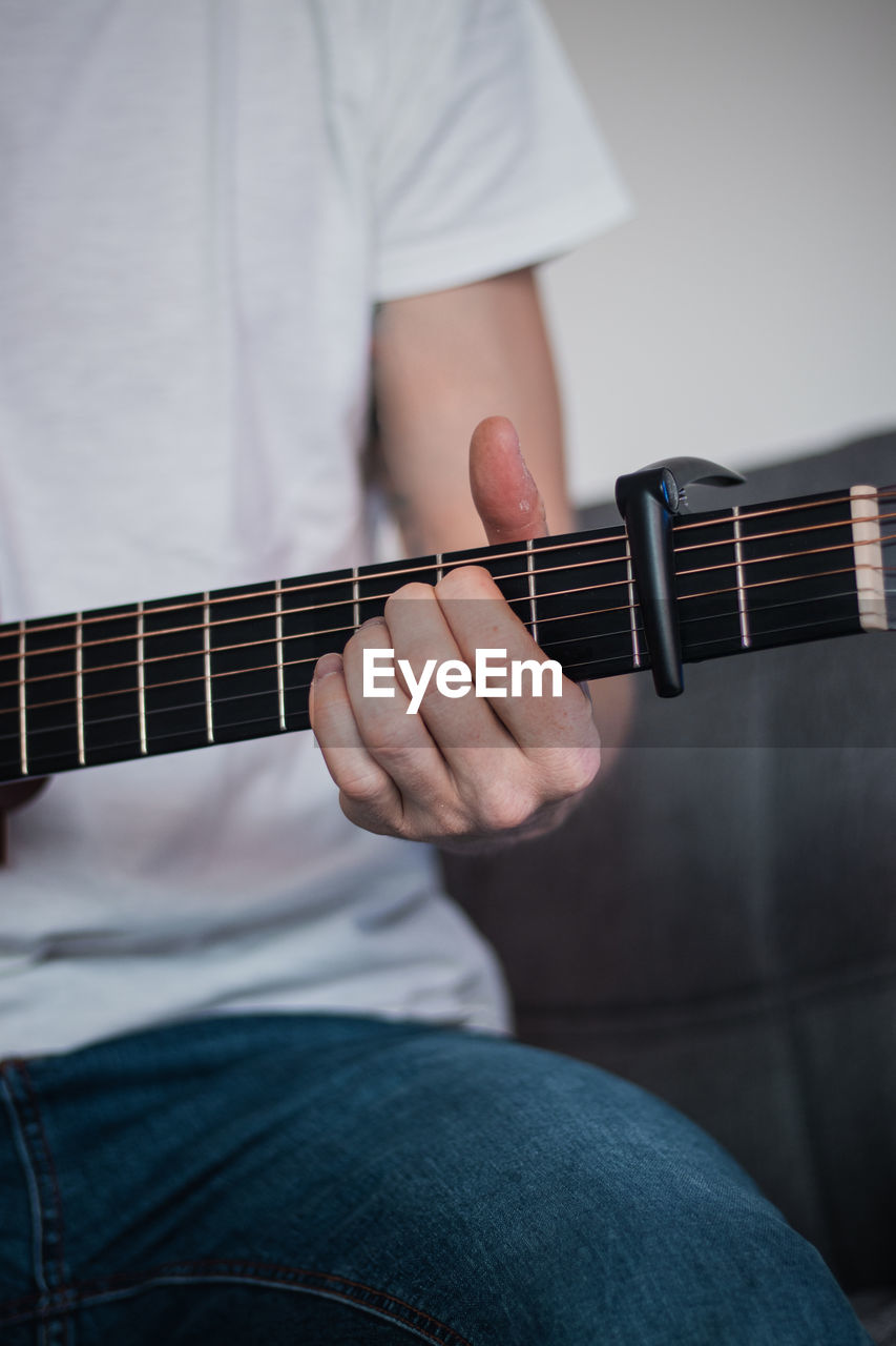 MIDSECTION OF MAN PLAYING GUITAR AT CAMERA