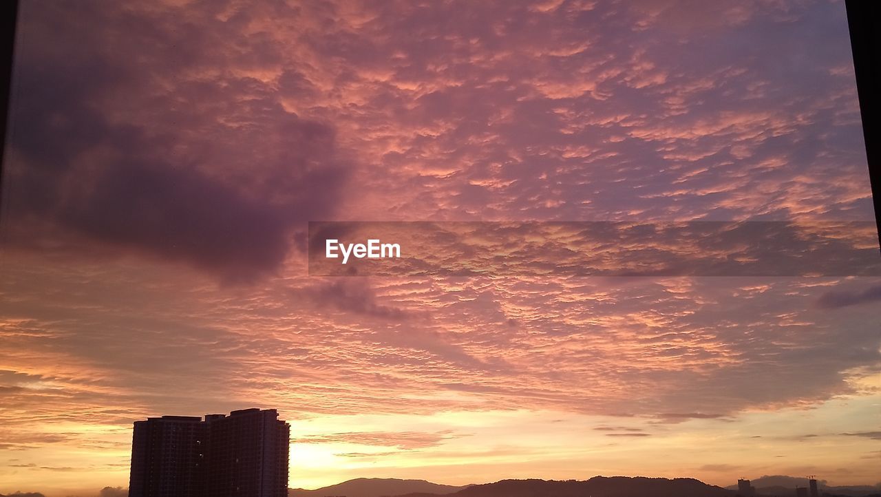 LOW ANGLE VIEW OF SILHOUETTE BUILDINGS AGAINST DRAMATIC SKY