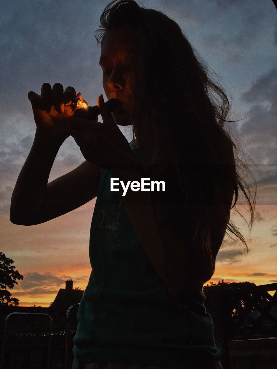 Woman smoking pipe at sunset