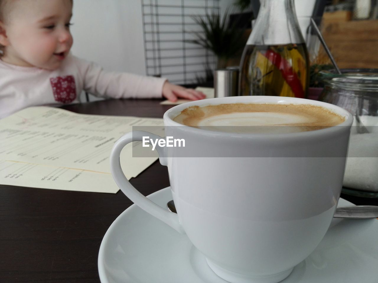 Close-up of coffee cup on table by baby girl at home