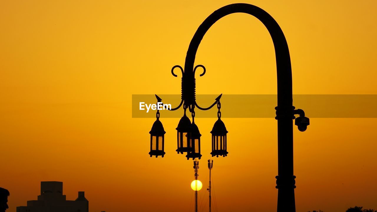 SILHOUETTE STREET LIGHT AGAINST ORANGE SKY DURING SUNSET