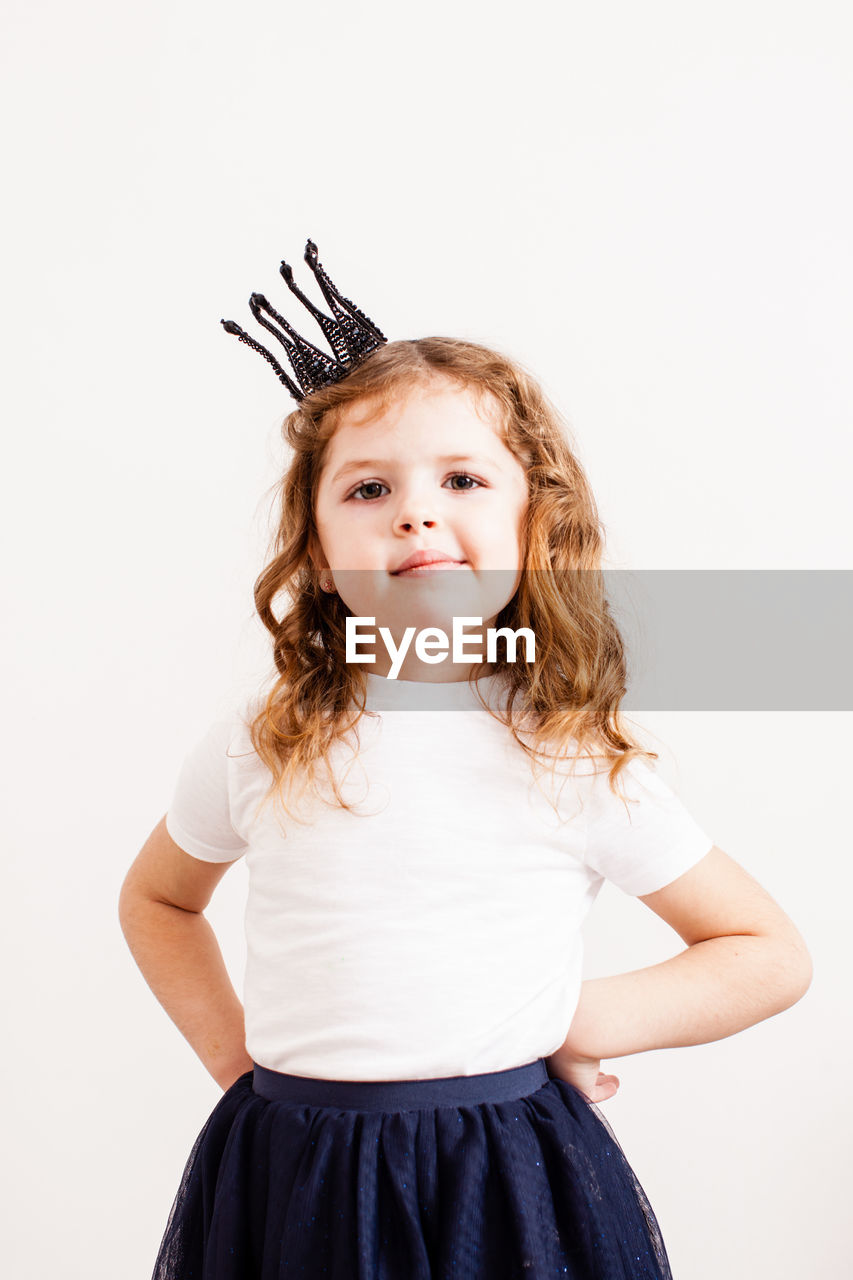 Portrait of cute girl standing against white background