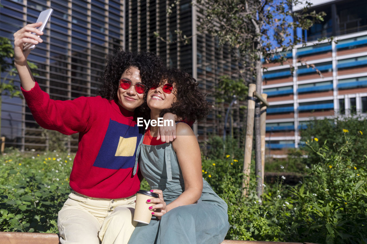 Smiling lesbian couple doing selfie while sitting outdoors