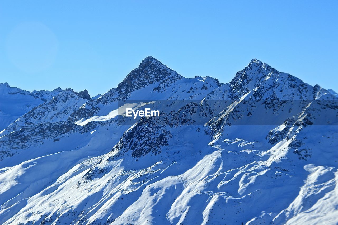 Scenic view of snowcapped mountains against clear blue sky