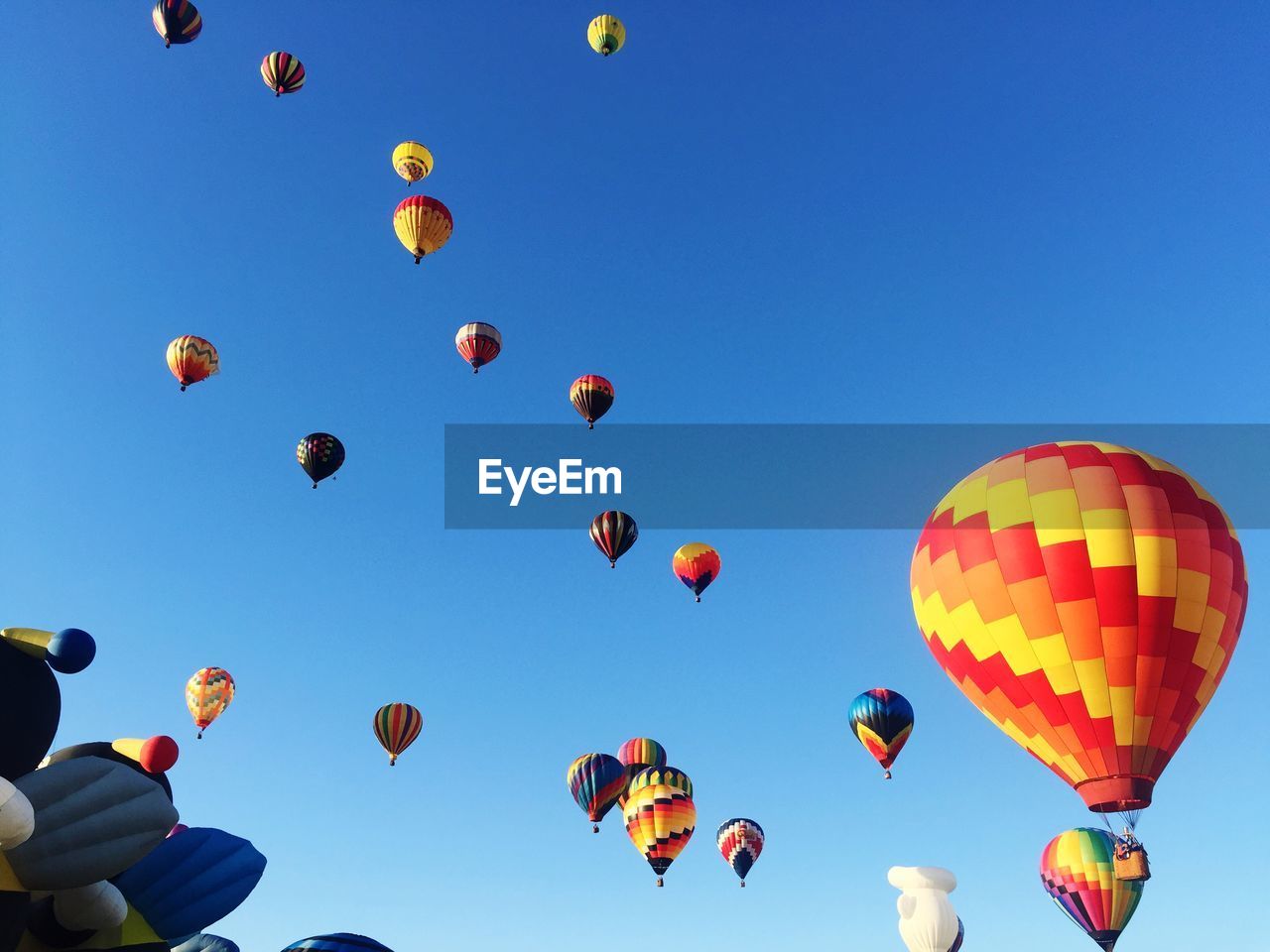 LOW ANGLE VIEW OF MULTI COLORED HOT AIR BALLOONS AGAINST BLUE SKY