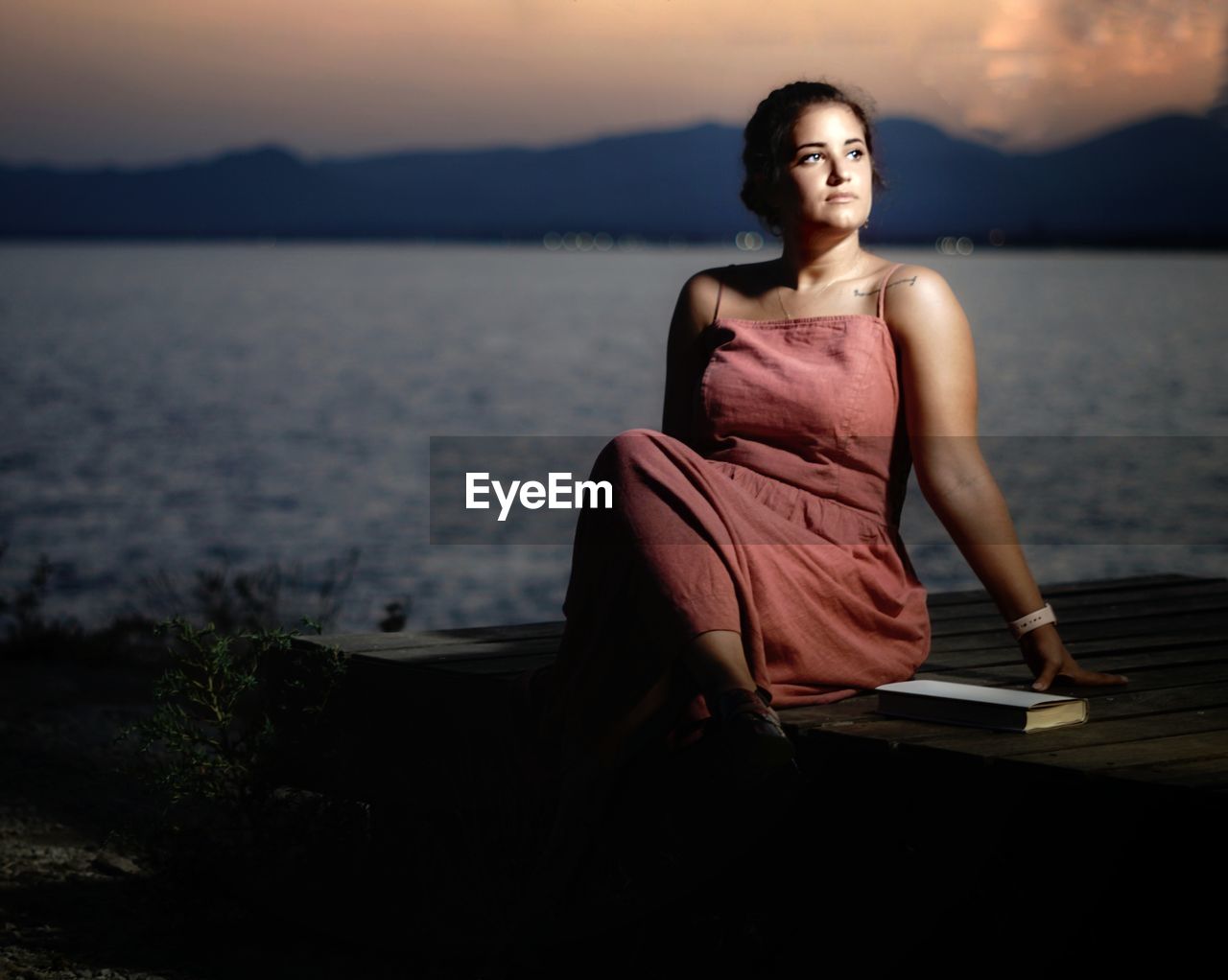 Portrait of a young woman sitting against sky