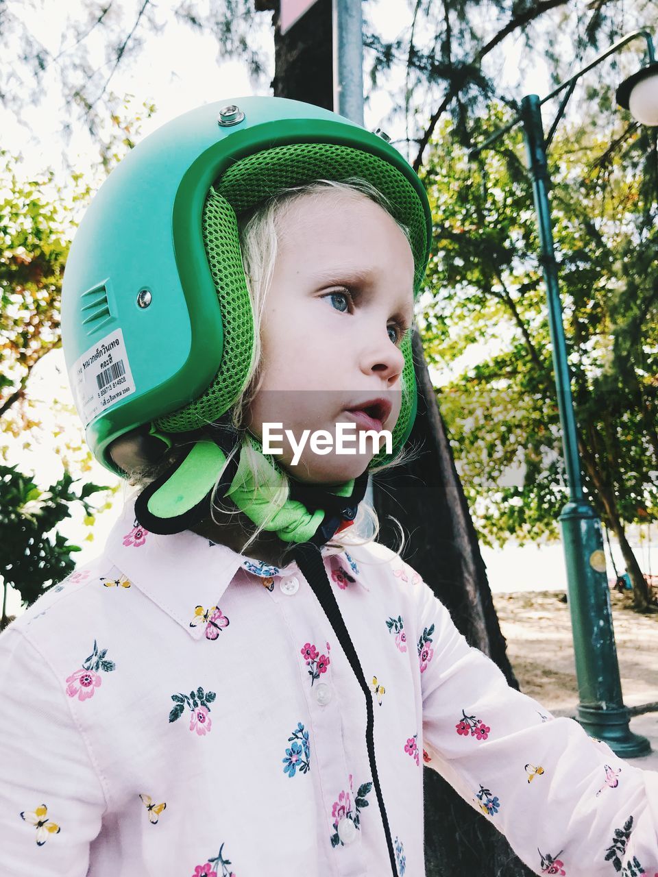 Cute girl wearing crash helmet against trees