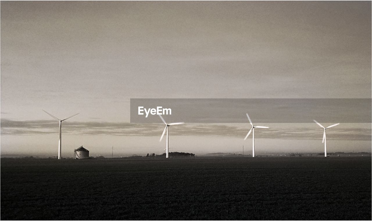 WIND TURBINES IN FIELD AGAINST SKY