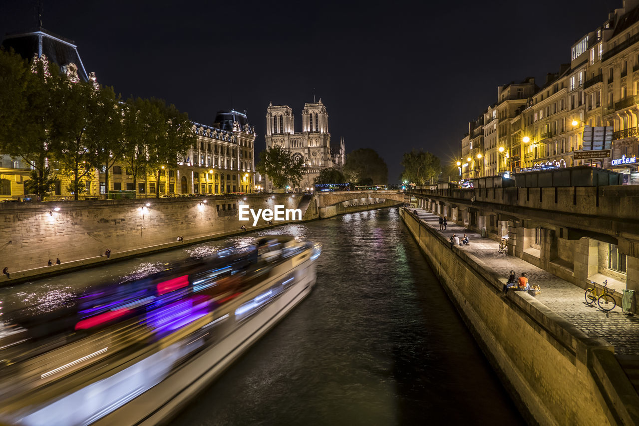 ILLUMINATED BRIDGE OVER RIVER AT NIGHT