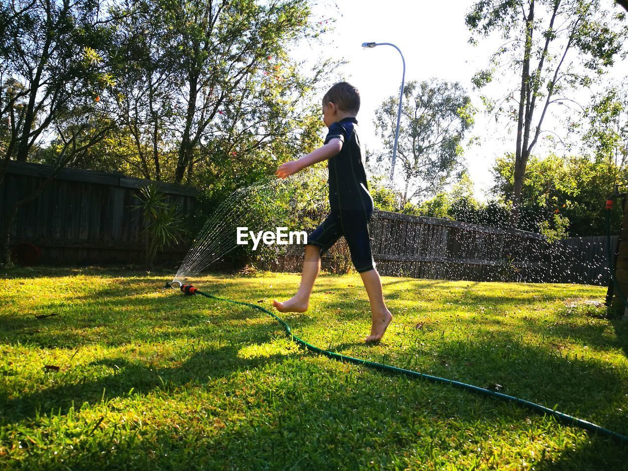 Boy playing with sprinkler in lawn