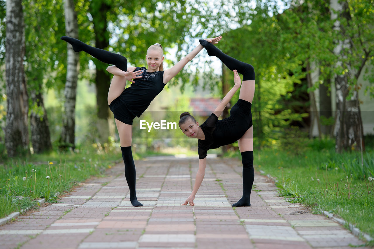 Portrait of girls practicing rhythmic gymnastics on footpath in park