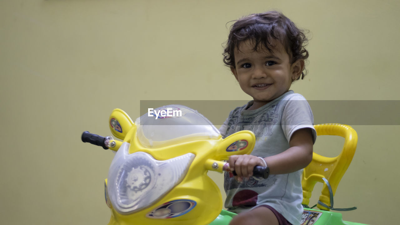 A little kid playing his car with a toy and feeling happy, at inside home