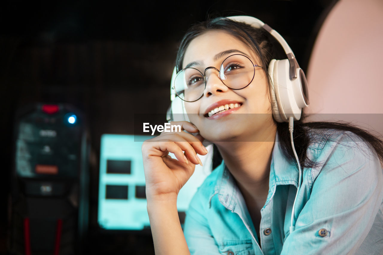 PORTRAIT OF SMILING YOUNG WOMAN HOLDING EYEGLASSES