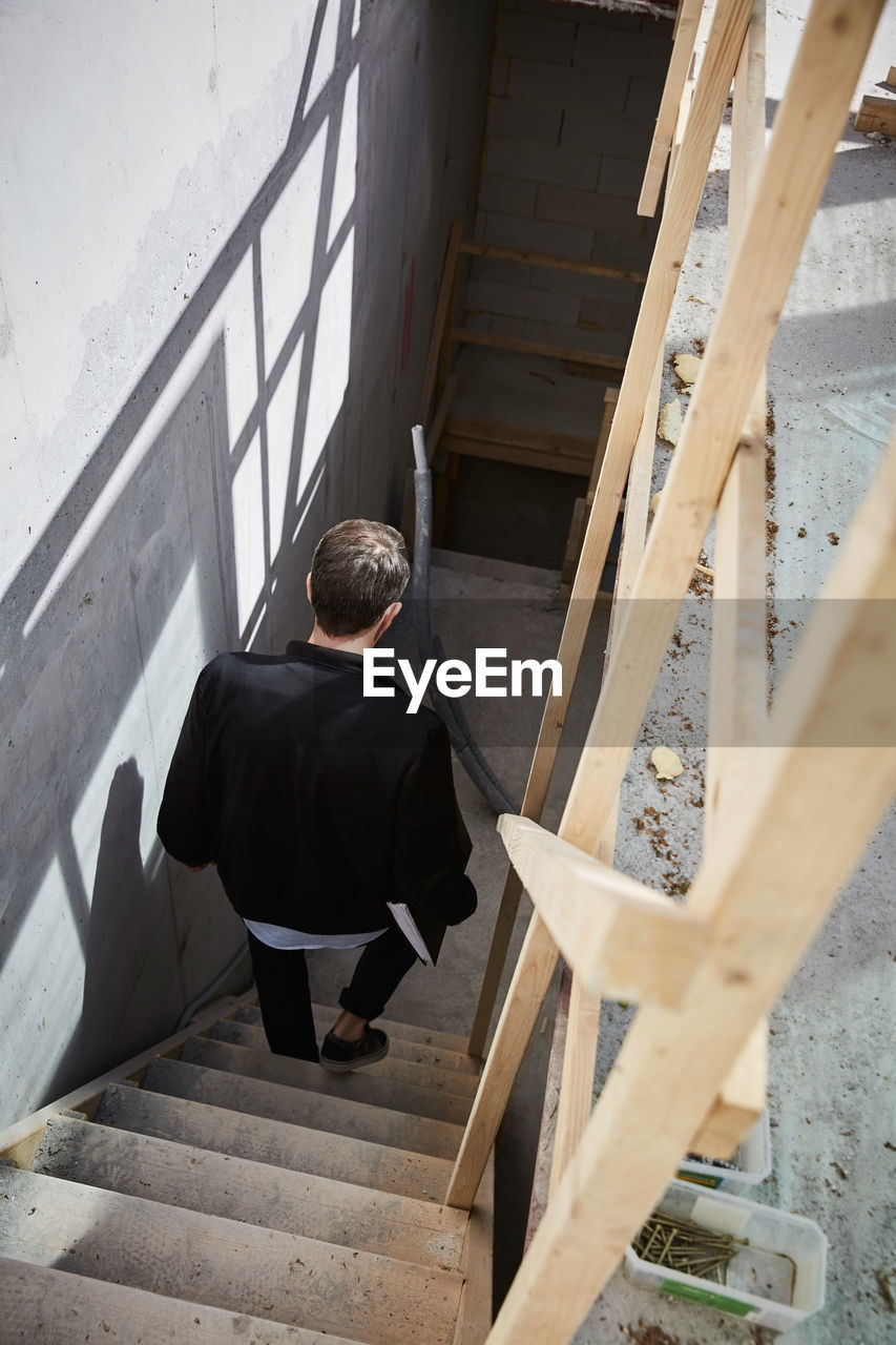 High angle view of architect moving down on steps at construction site