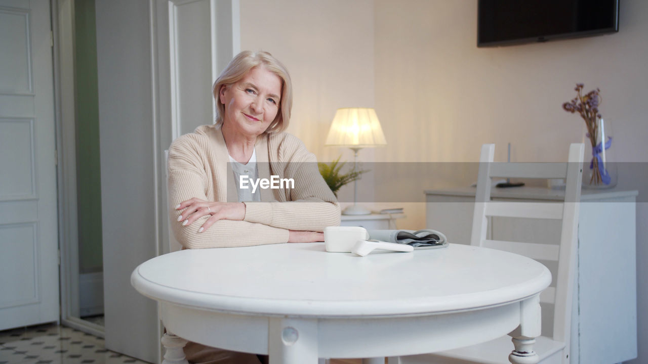 Portrait of smiling woman sitting on chair by table