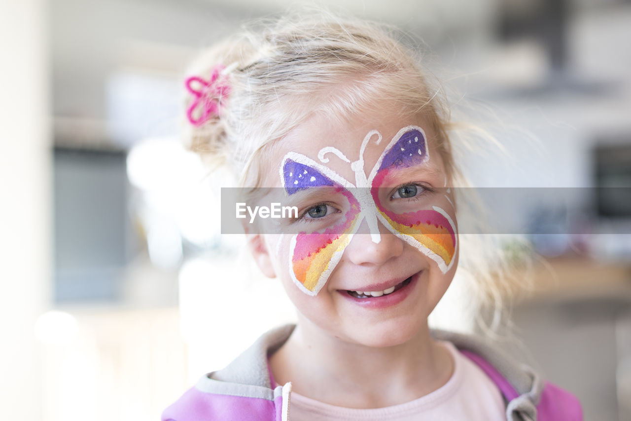 Portrait of smiling girl with painted butterfly on face