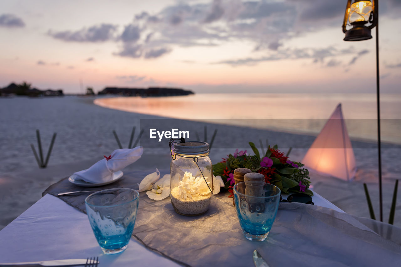 Objects on table at beach during sunset