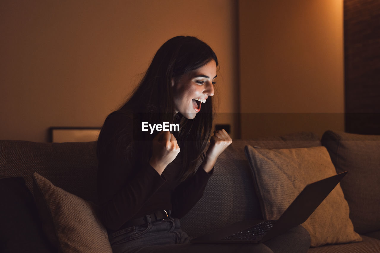 side view of young woman looking away while sitting on sofa at home