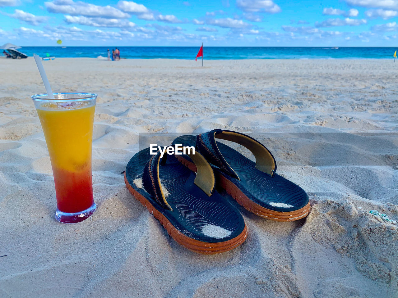 CLOSE-UP OF DRINK ON SAND AT BEACH